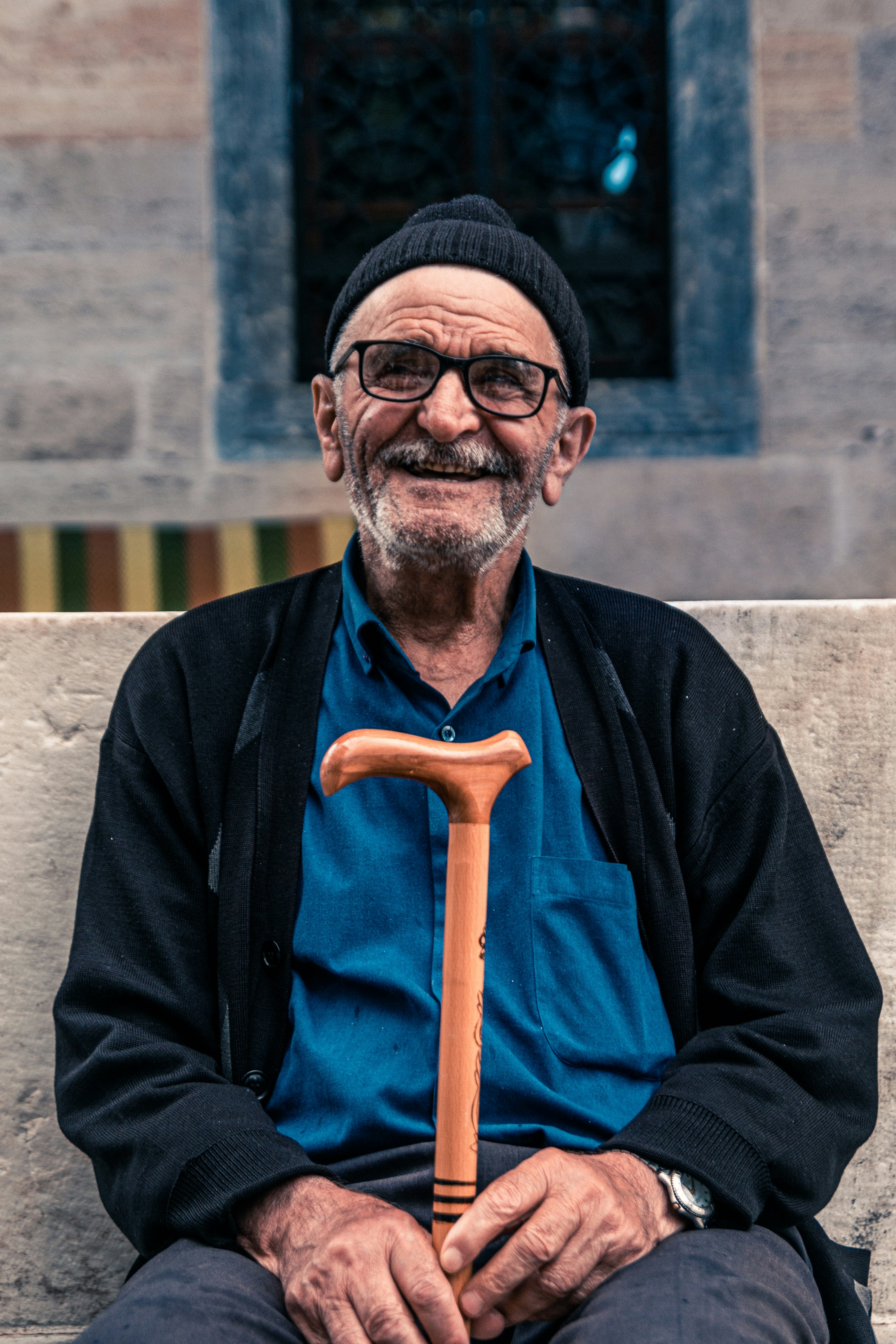 Homme âgé souriant assis sur un banc tenant une canne